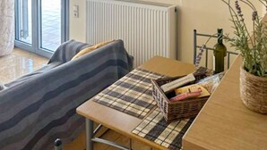 Ein Zimmer mit einer Couch, einem kleinen Tisch mit einem Korb, einem Heizkörper und einer Klimaanlage.