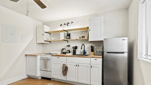 A modern kitchen with white cabinets, a stainless steel refrigerator, wooden countertops, and a built-in oven.