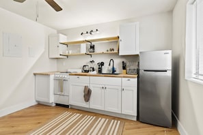 Eine moderne Küche mit weißen Schränken, einem Edelstahlkühlschrank, Holz Arbeitsplatten und einem eingebauten Backofen.