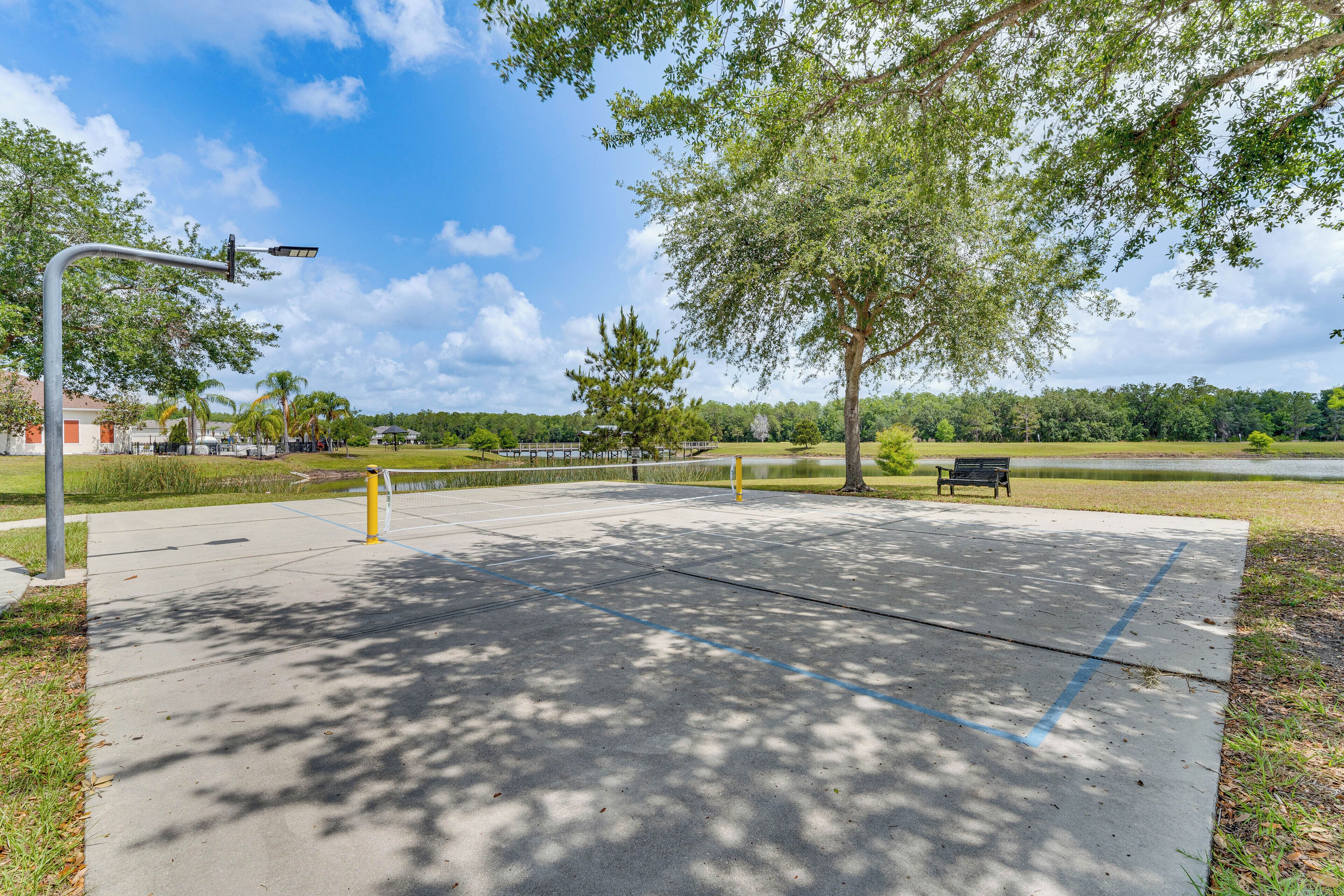 A park with a paved area, a bench, and a street lamp.