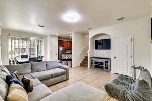 A living room with a sectional sofa, a grey armchair, and a TV mounted on an archway. - Pool, Hot Tub & Theatre Access: Kissimmee Gem (Kissimmee)