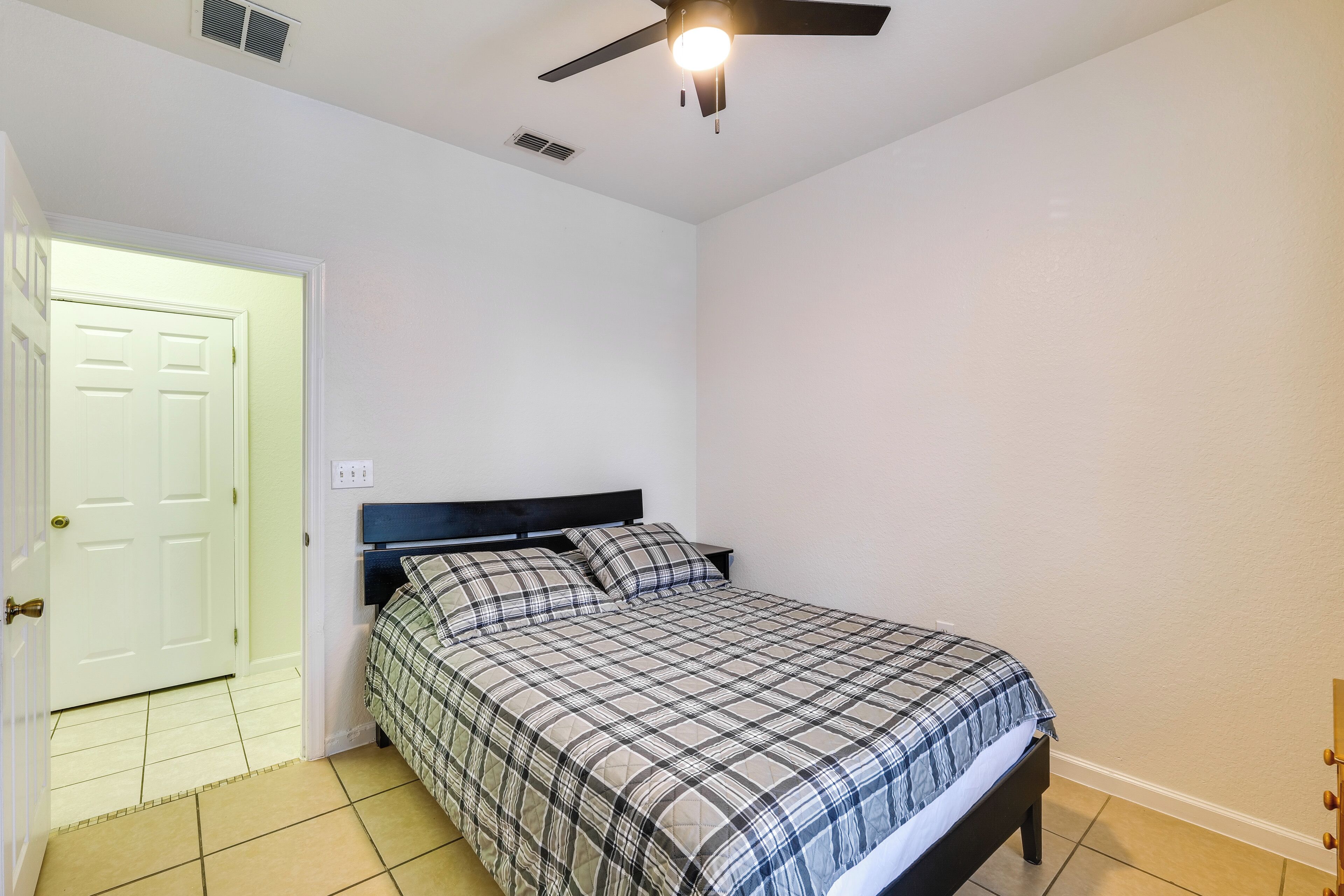 A bedroom with a bed, a ceiling fan, and a door.