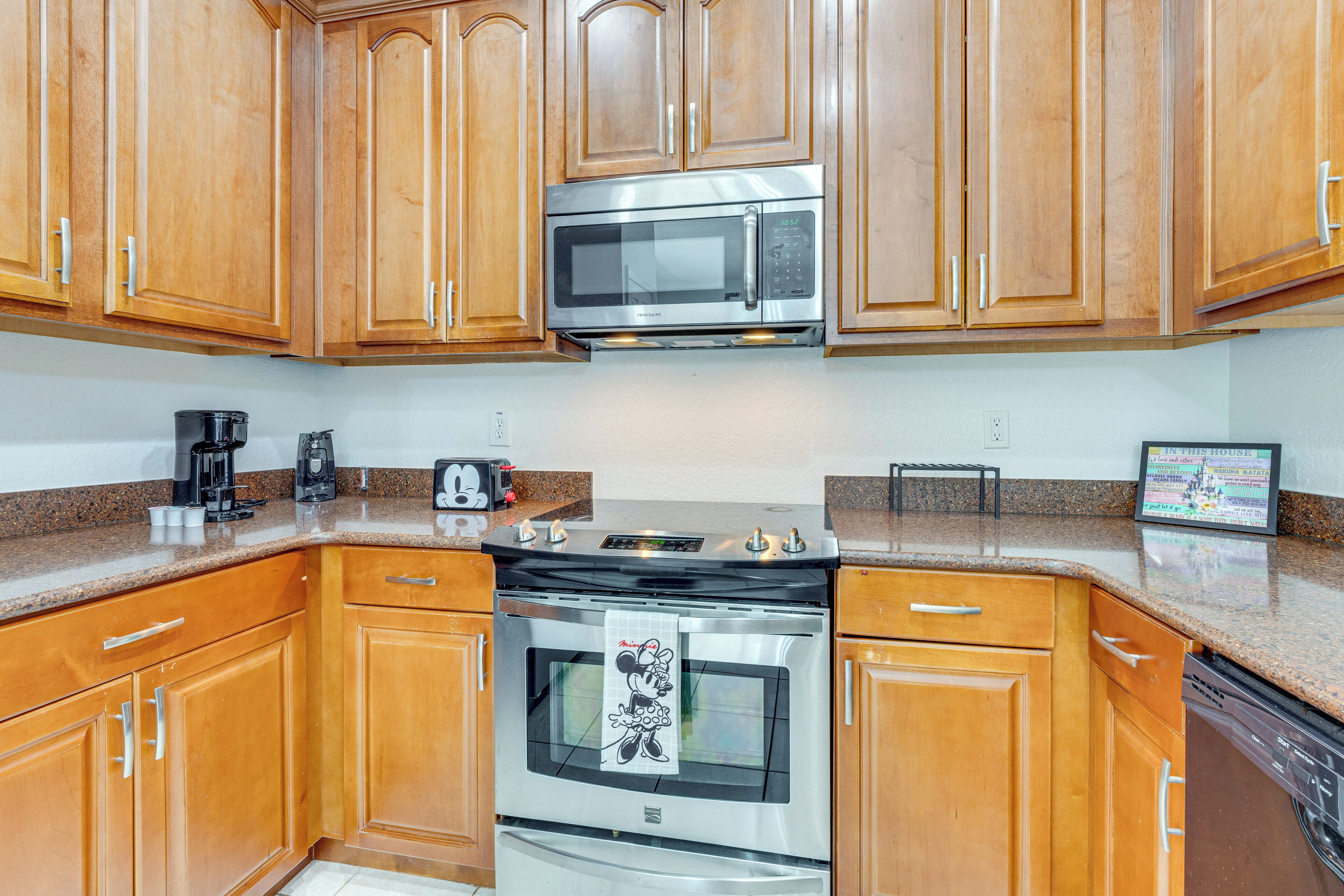 A kitchen with wooden cabinets, a stainless steel microwave, a stove, and a coffee maker.