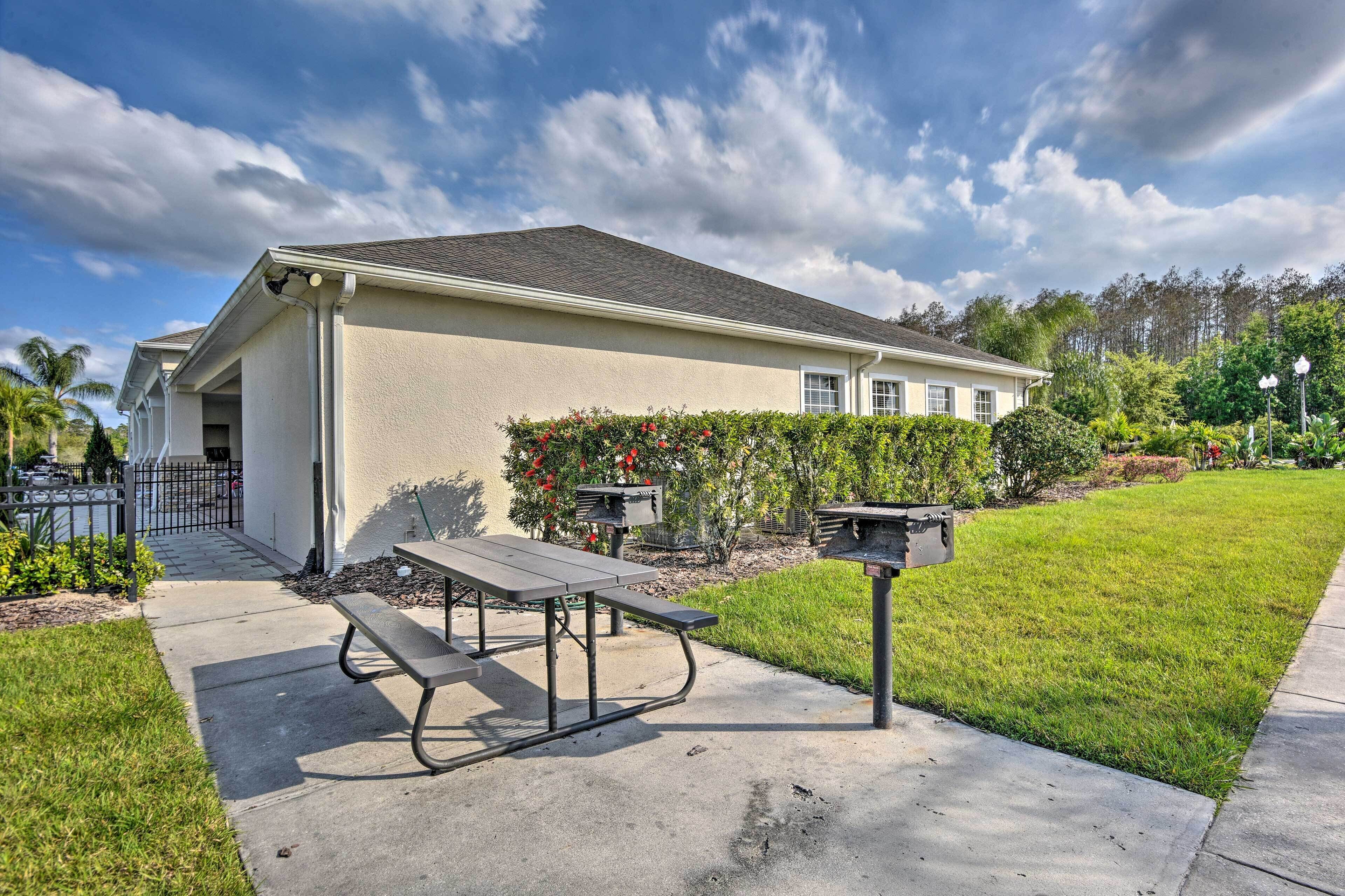 A single-story building with a flat roof, a concrete patio with a picnic table and benches, and a mailbox.