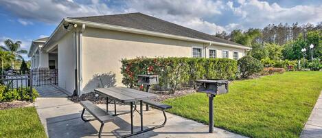 A single-story building with a flat roof, a concrete patio with a picnic table and benches, and a mailbox.