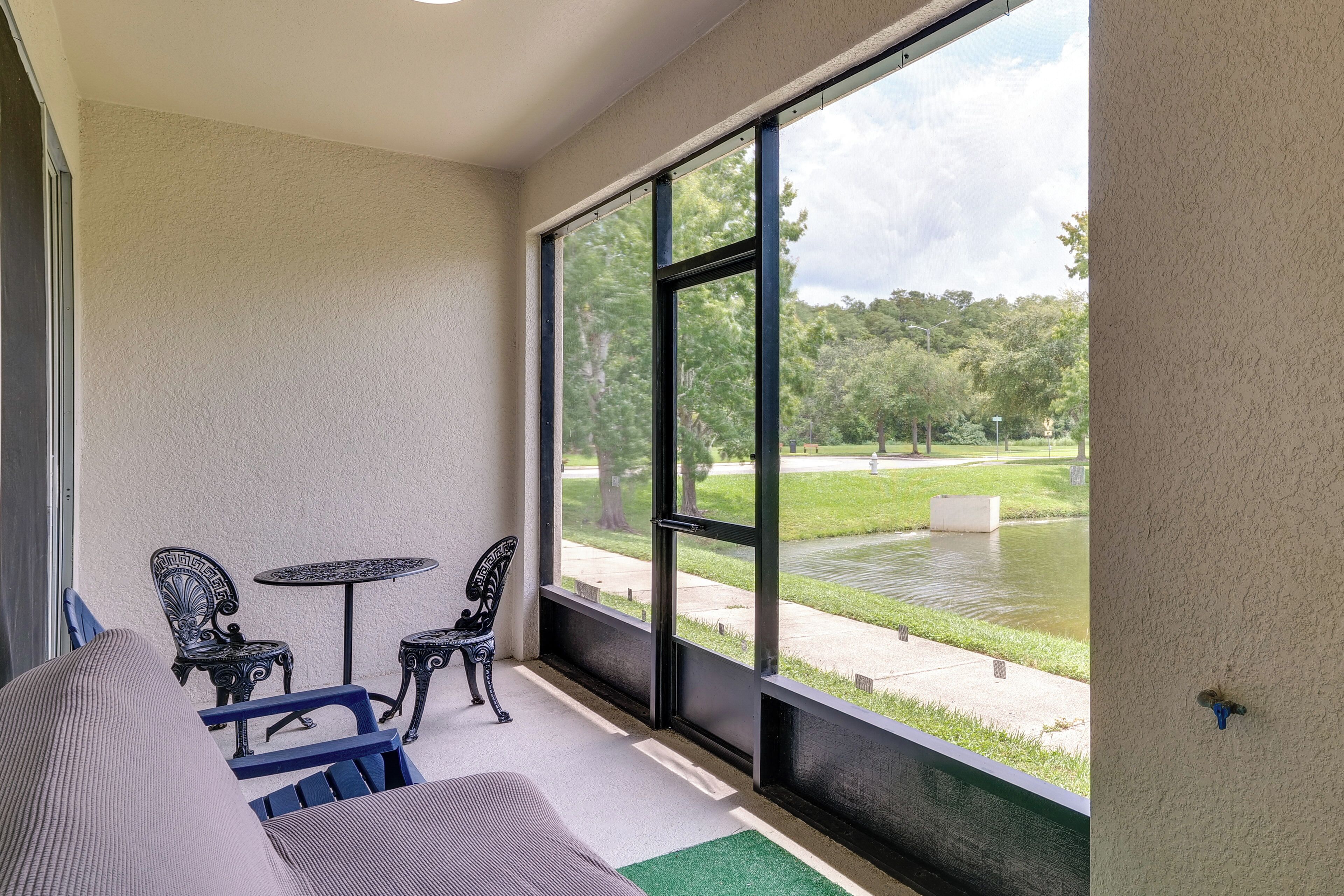 Ein Balkon mit Blick auf einen Park und einen Teich, ausgestattet mit einer Couch und zwei Sesseln.