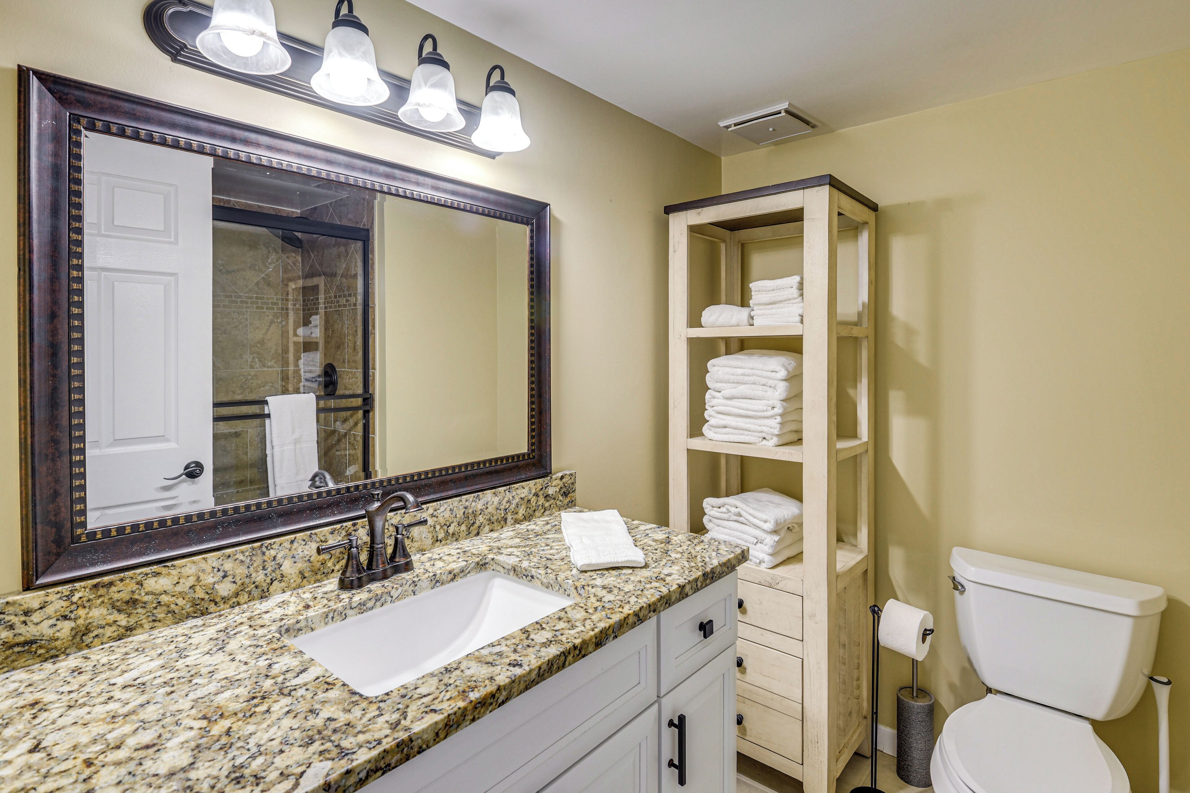 Une salle de bain avec un lavabo en granit, un grand miroir, des toilettes et un porte-serviettes.