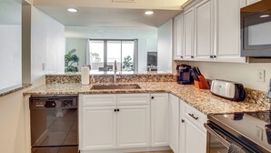 A modern kitchen with white cabinets, granite countertops, a dishwasher, a stove, and a microwave.