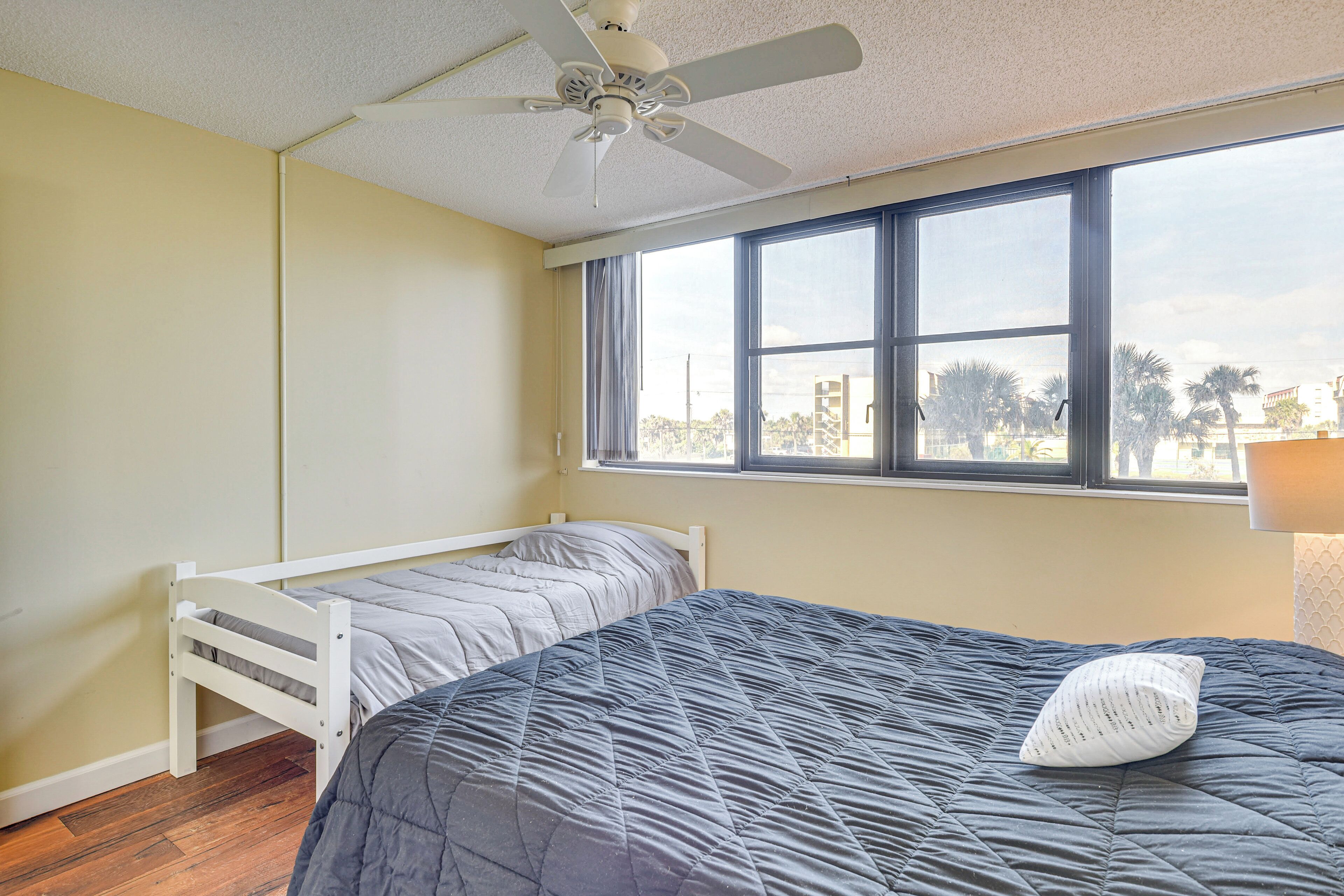 A bedroom with a single bed, a window, and a ceiling fan.