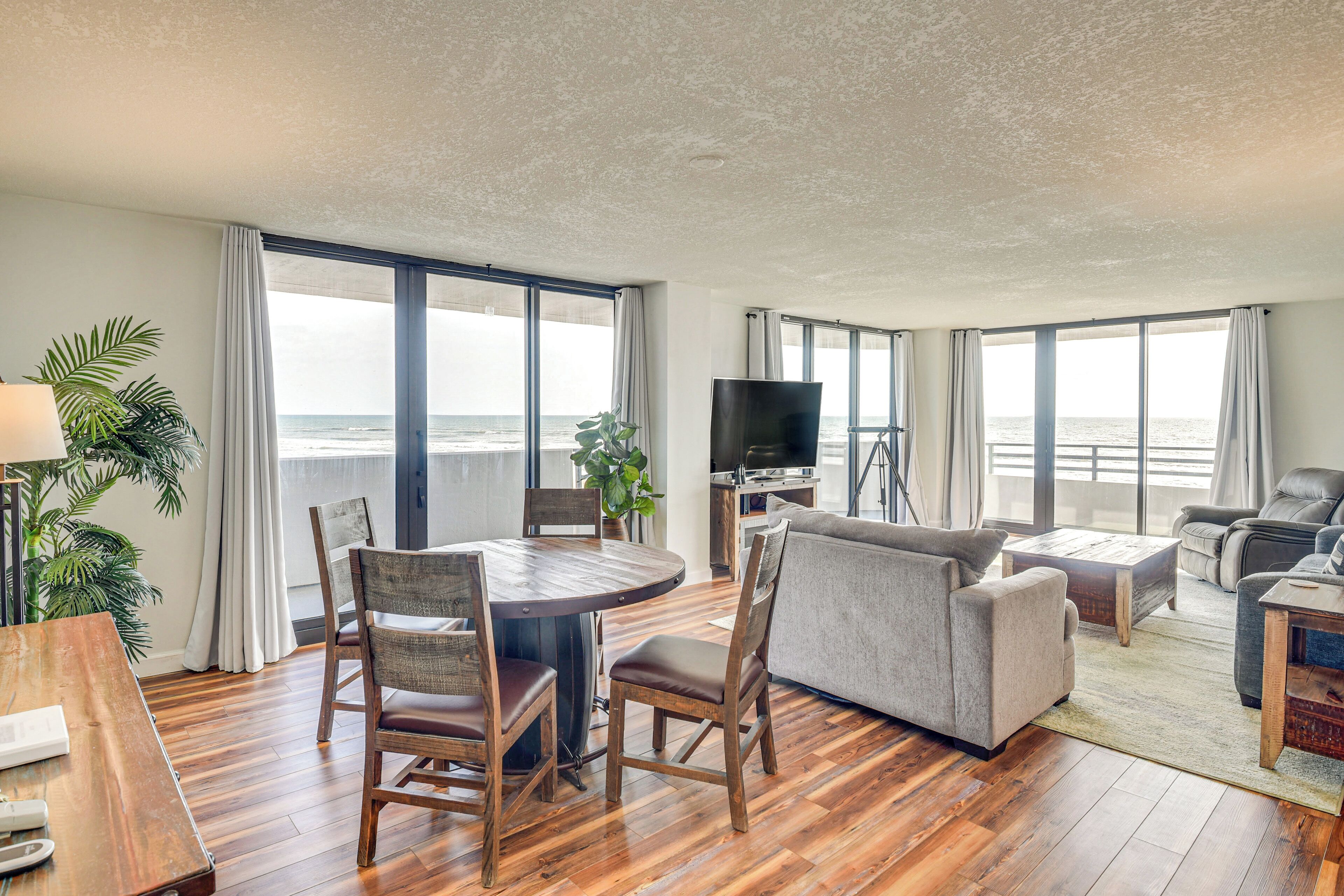 A spacious living room with a wooden floor, a round dining table, and a sofa.