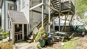 A two-story house with a wooden deck, a small outdoor kitchen area, and a front porch. - Explore Dtwn, Parks & Colleges: Cozy Worcester Apt (Worcester)