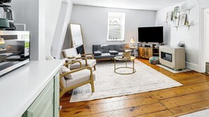 A modern living room with a sofa, coffee table, and a flat-screen TV. - Explore Dtwn, Parks & Colleges: Cozy Worcester Apt (Worcester)