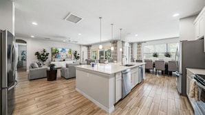 A modern kitchen with a central island, built-in appliances, and a dining area with a table and chairs.