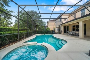 A swimming pool with a hot tub, surrounded by a covered patio area with outdoor furniture.