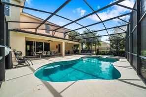 A covered outdoor swimming pool area with lounge chairs and a patio table. - Spacious Home w/ Private Pool/Spa! *Sleeps 21* (Davenport)