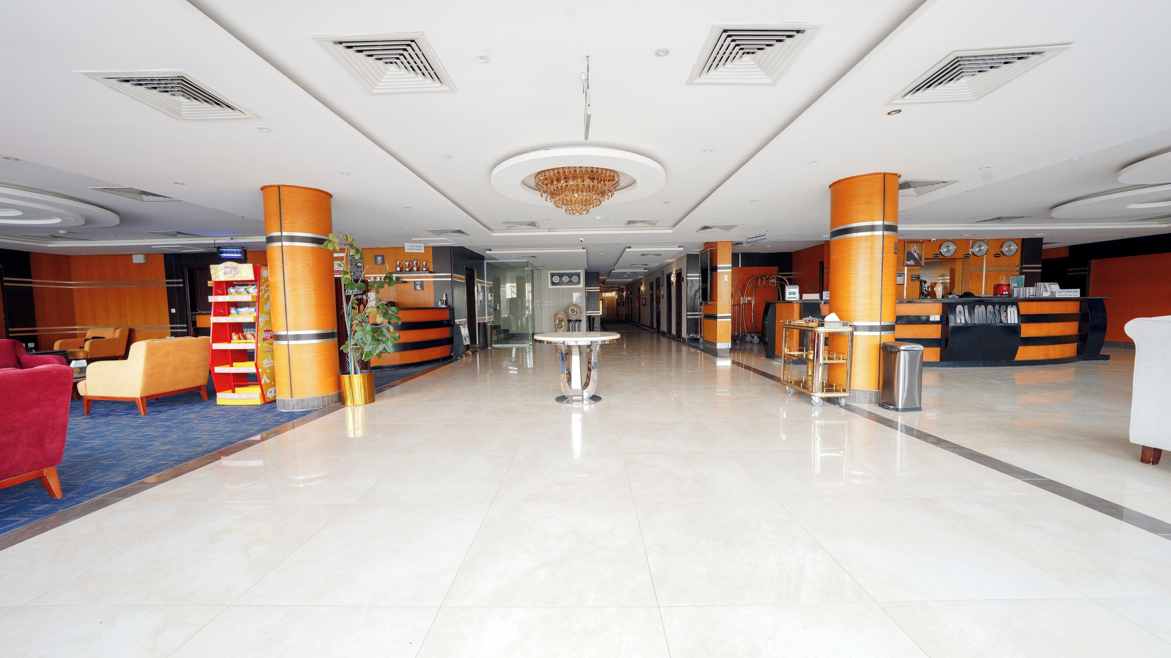 A hotel lobby with a reception desk, seating area, and a chandelier.