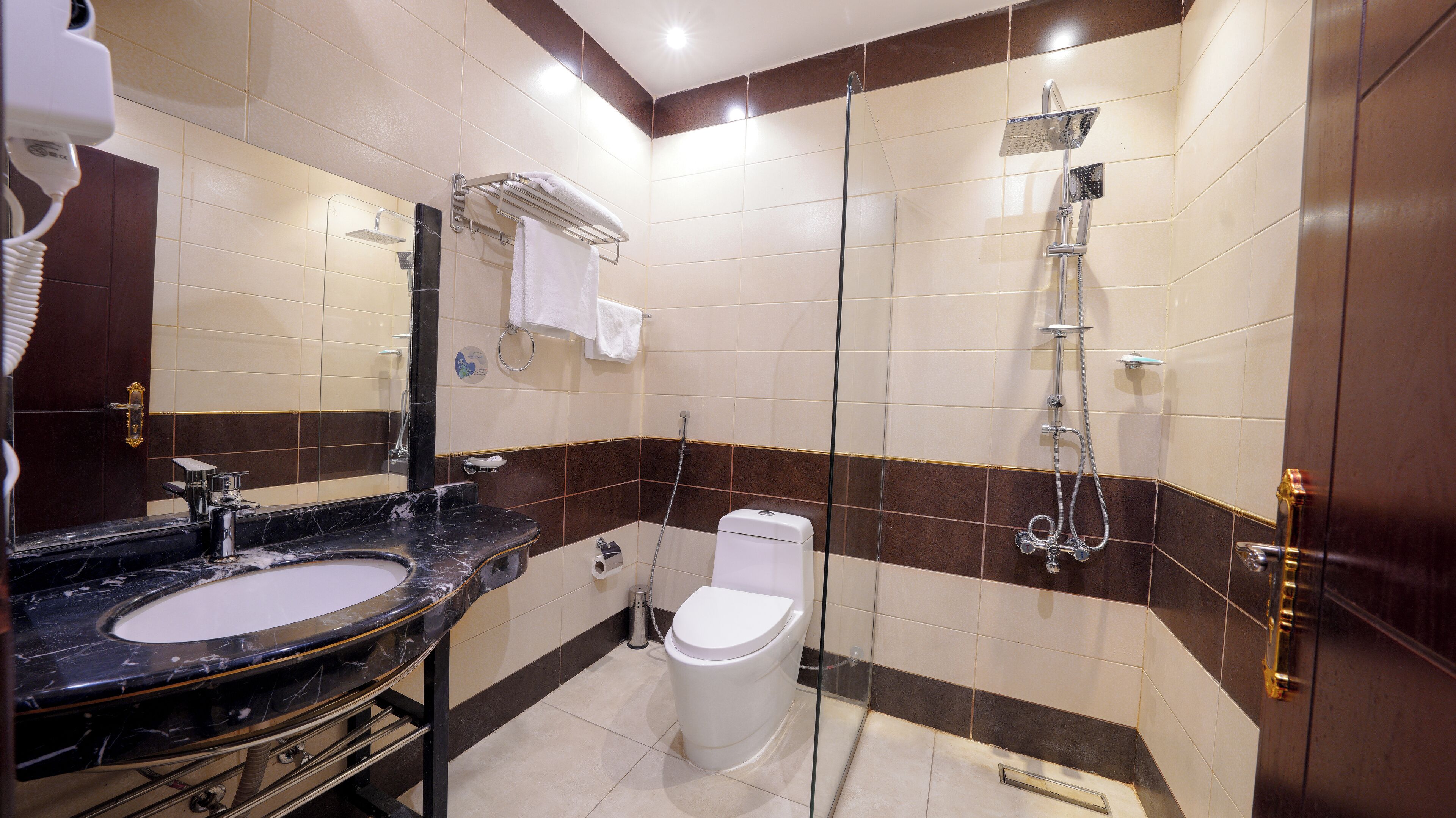 Un baño moderno con lavamanos de mármol, inodoro y cabina de ducha con paredes de vidrio.