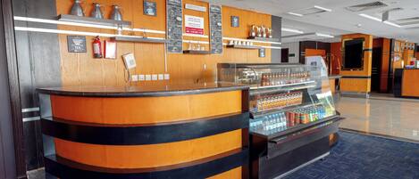 A hotel reception area with a counter, a coffee station, and a beverage display.