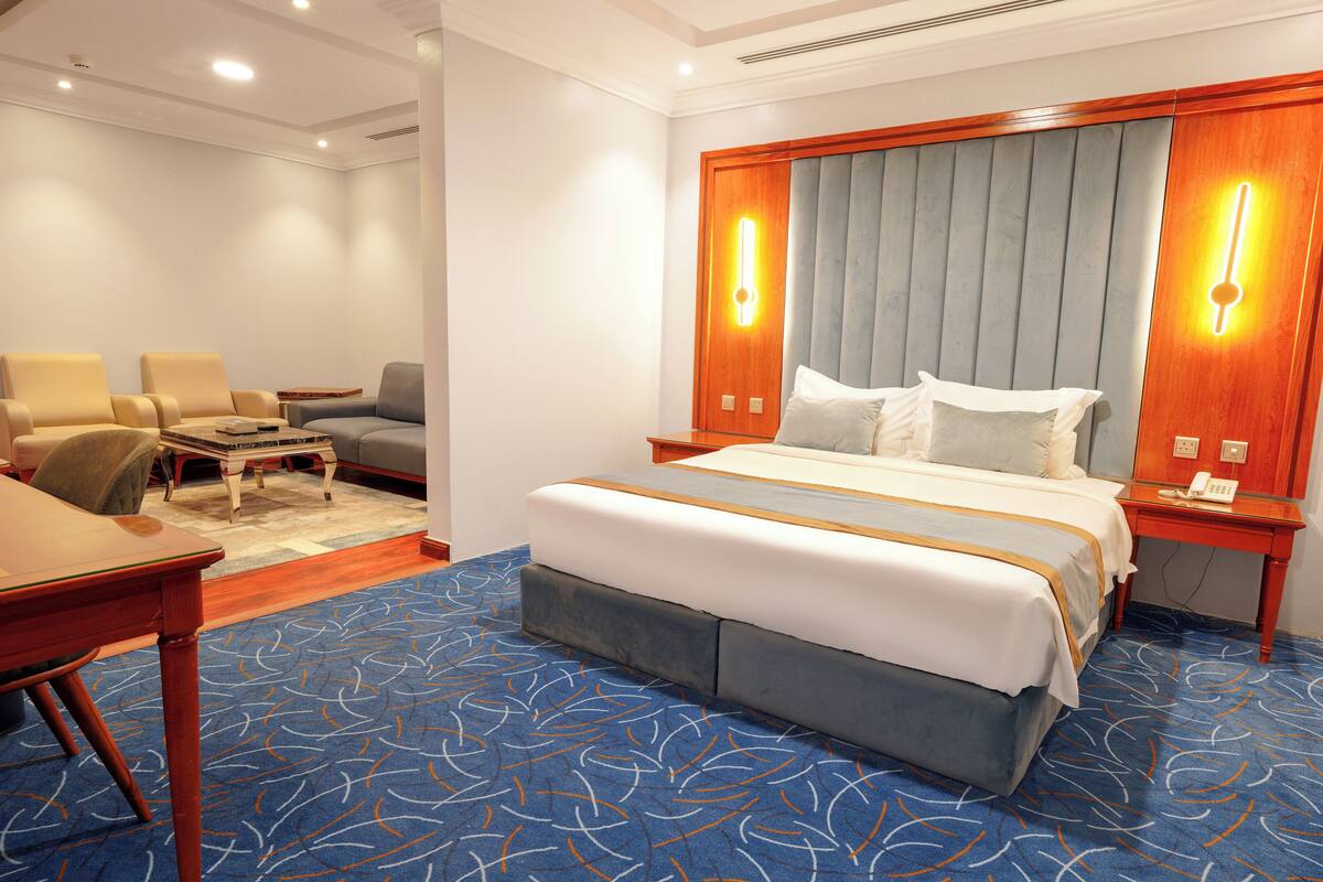 A hotel room with a bed, a desk, a chair, and a sofa.