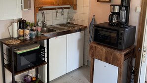 Een compacte keuken met houten kastjes, een inbouwoven, een magnetron en een koffiezetapparaat.