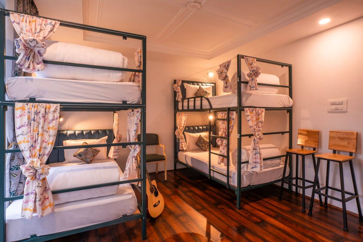 A dormitory room with bunk beds, a guitar, and a small table.