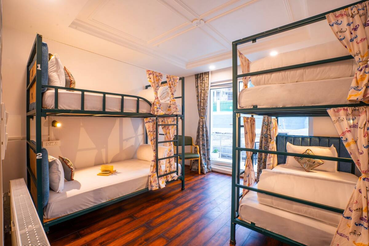 A room with two bunk beds, a small table, and a chair.