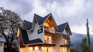 A modern two-story house with a balcony, a driveway, and a car parked in front. - Moustache Pahalgam (Anantnag)