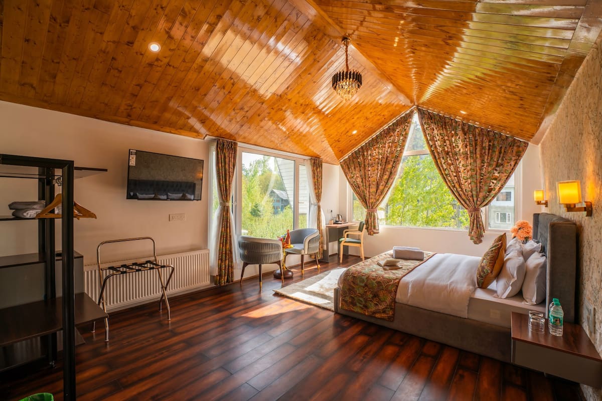 A bedroom with a wooden ceiling, a bed, a desk, and a chair.