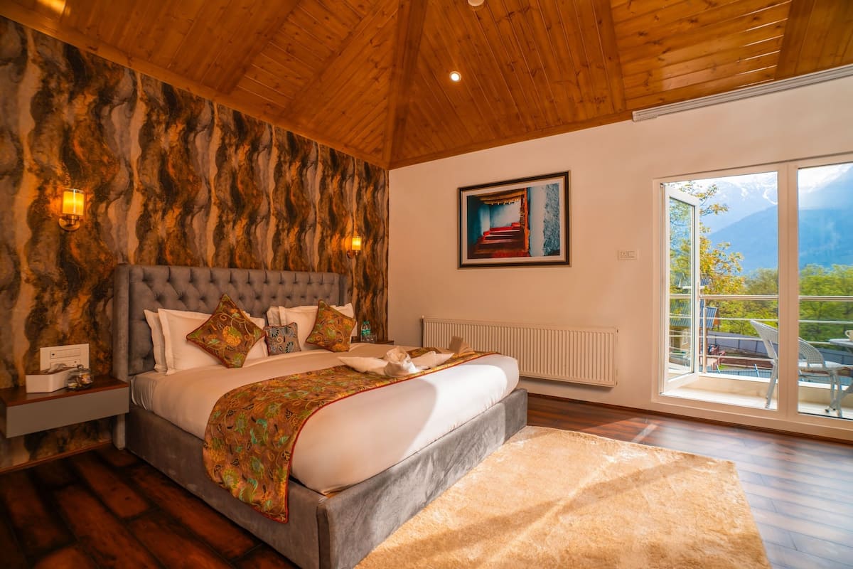 A spacious bedroom with a large bed, wooden ceiling, and a view of the outdoors.