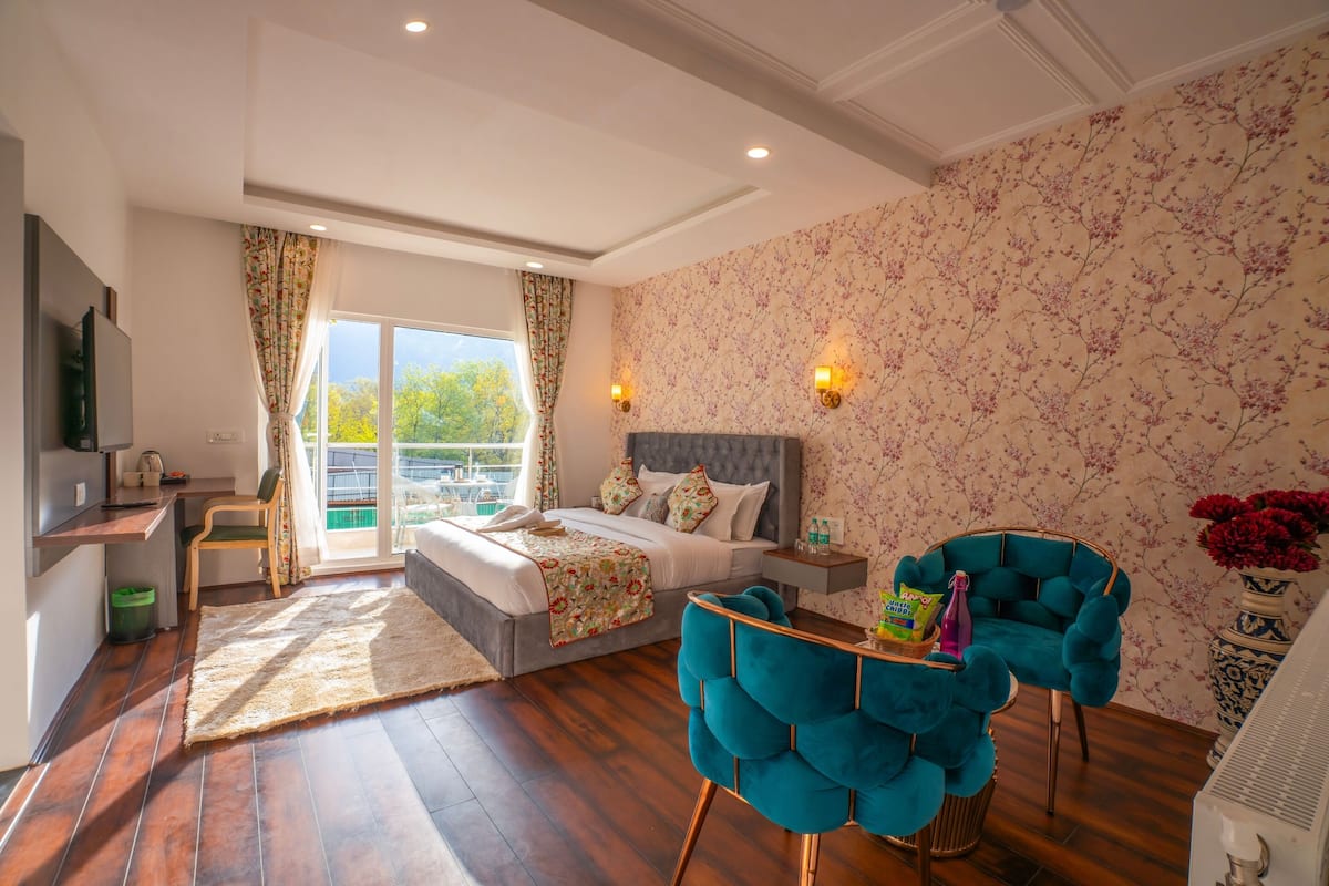 A hotel room with a bed, a desk, a chair, a TV, and a view of the outdoors.