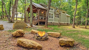 A cabin with a deck, surrounded by trees and a fire pit. - Secluded Bluebell Cottage with Private Fire Pit! (Menlo)