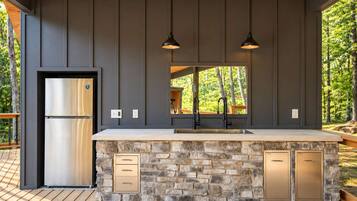 A modern kitchen with a stone island, stainless steel refrigerator, and pendant lighting.