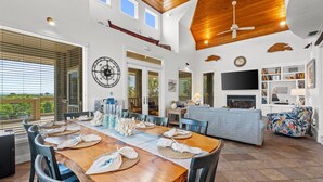 Amplia sala de estar con techo de madera, mesa de comedor para cuatro personas y una zona de estar cómoda con sofá y sillones.