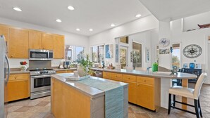 Una cocina moderna con armarios de madera, electrodomésticos de acero inoxidable y una isla central.