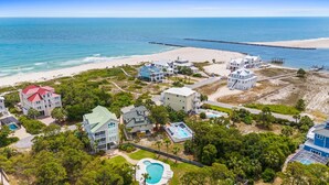 Un complejo turístico frente al mar, con varias edificaciones, una playa y un muelle.
