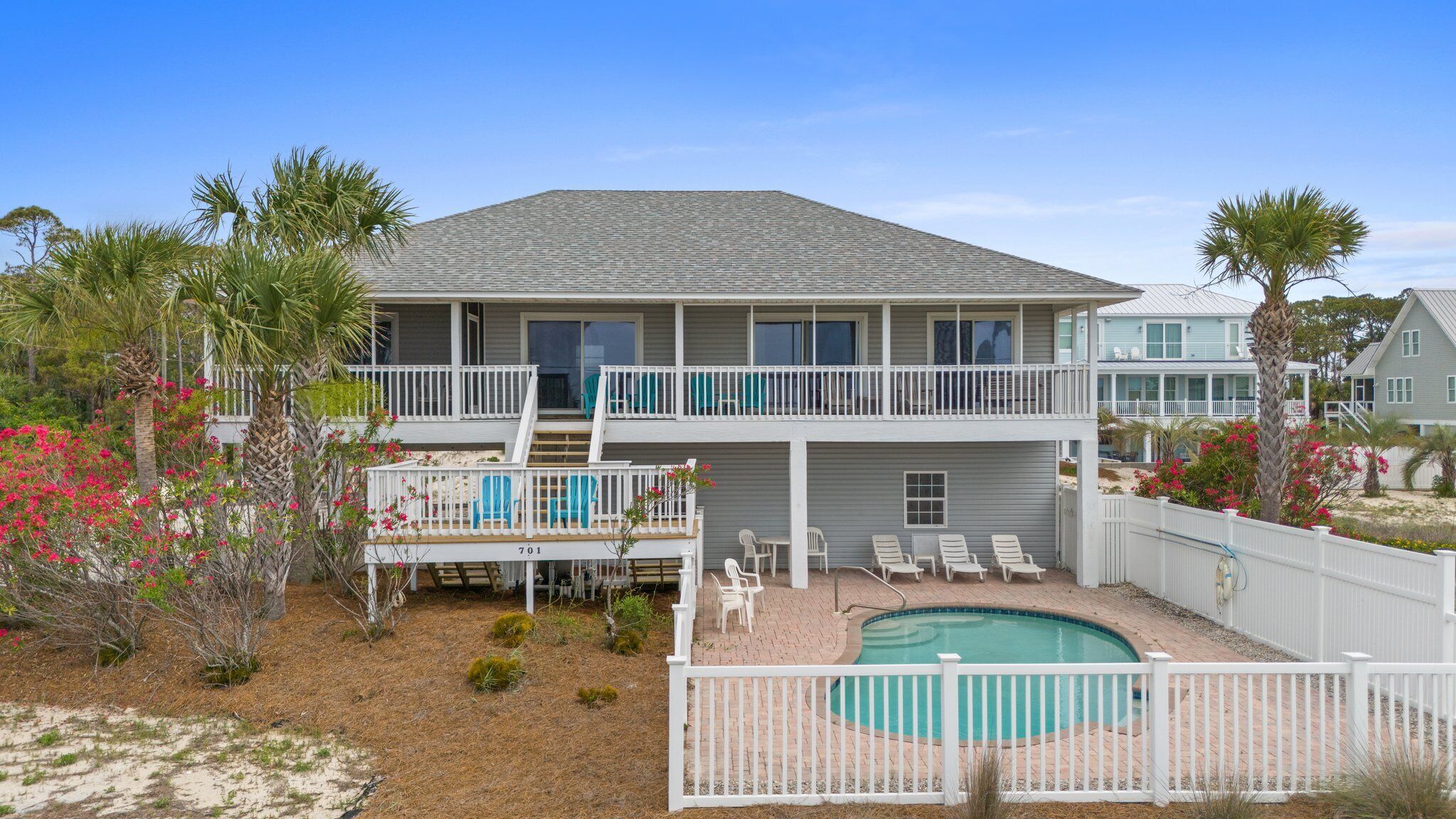 A two-story house with a pool, a covered deck, and a fenced backyard.