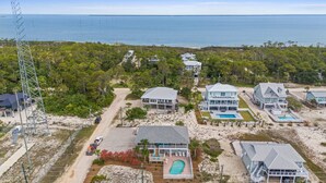 A coastal property with multiple houses, a swimming pool, and a view of the ocean.