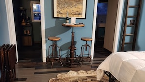 A bedroom with a bunk bed, a round coffee table, two stools, a large rug, and a painting on the wall. - Muskegon Lake View Loft studio/kitchenette (Muskegon)