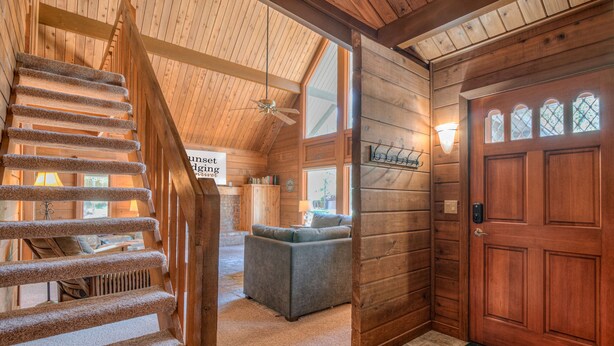 A wooden interior with a staircase, a sofa, and a door with windows.