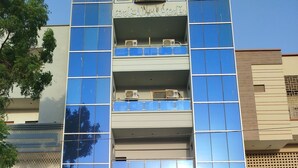 A multi-story building with a reflective glass facade, a sign for Karachi Law Associates, and a motorcycle parked in front. - Hotel Crown Plaza (Karachi)