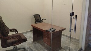 A room with a wooden desk, a chair, a telephone, and a glass partition. - Hotel Crown Plaza (Karachi)