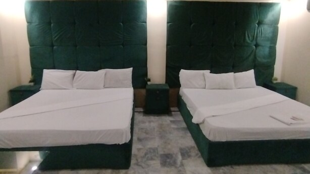 A hotel room with two beds, a marble floor, and a green upholstered headboard. - Hotel Crown Plaza (Karachi)