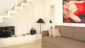 A modern living room with a staircase, a flat-screen TV, a sofa, and a painting. - Room-pistis Room - Santa Sofia Martano (Martano)