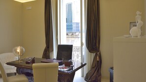 A hotel room with a dining area featuring a table, chairs, and a lamp. There is a window with curtains, an air conditioning unit, and a decorative statue on a pedestal. - Room-pistis Room - Santa Sofia Martano (Martano)