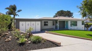 A modern single-story house with a front yard, a driveway, and a garage. - 4BR | Hilltop House Sunset Cliffs | Beach, Bars, Ocean View (San Diego)