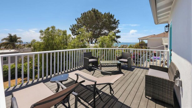 A balcony with outdoor furniture, a white railing, and a view of the sea. - 4BR | Hilltop House Sunset Cliffs | Beach, Bars, Ocean View (San Diego)