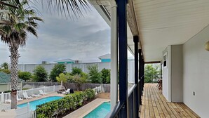 A covered outdoor area with a wooden deck, a swimming pool, and lounge chairs. - Serenity Cottage | Gulfside Community, Private Pool + Bikes (Miramar Beach)