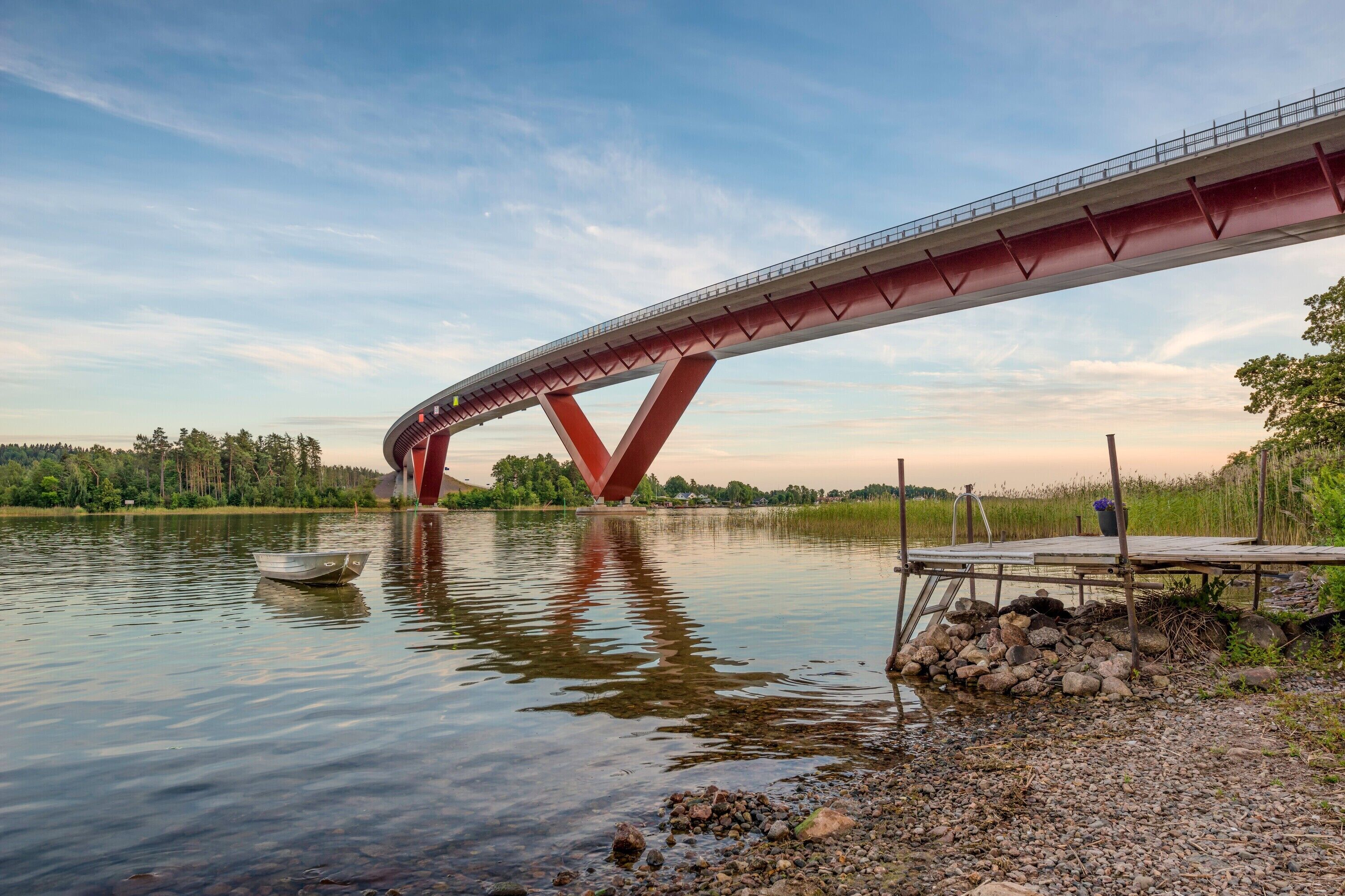 Un pont enjambant une rivière paisible, avec un petit bateau sur l’eau.