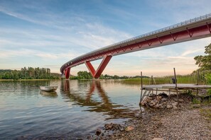 A bridge over a calm river with a small boat on the water. - Charming Swedish Forest Cottage Motala (Motala)