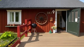 A red wooden house with a number 302, a large wheel, a barbecue, and a green door. - Charming Swedish Forest Cottage Motala (Motala)